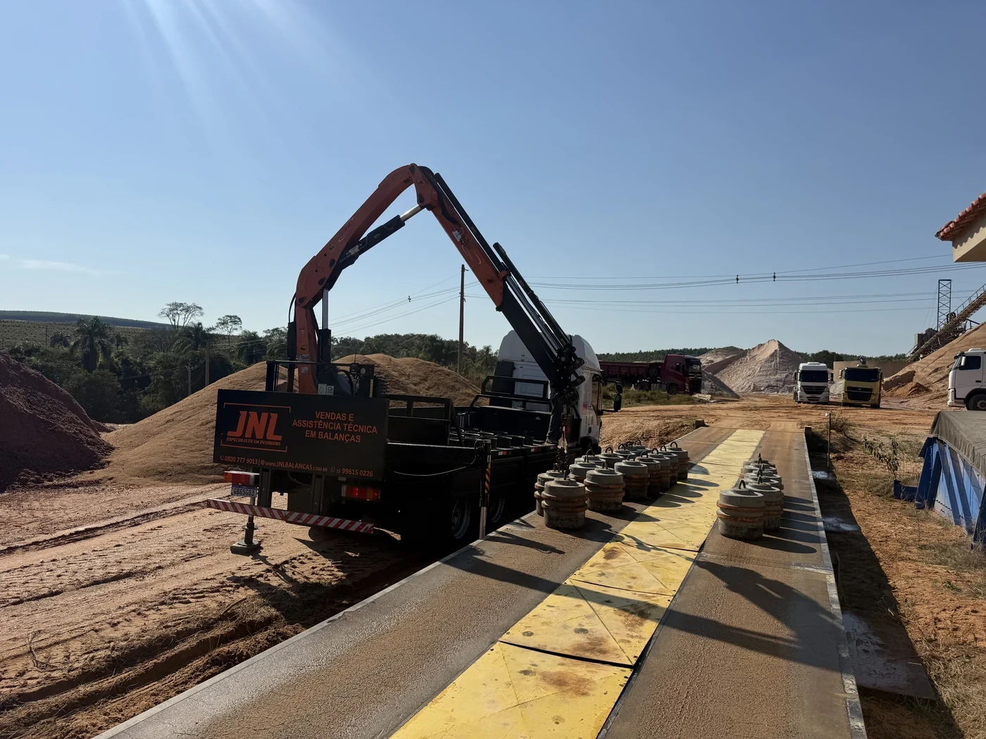 Caminhão com guindaste e pesos em balança rodoviária